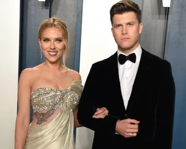 A couple poses together at an event, the woman wearing a bejeweled gown and the man in a black tuxedo.