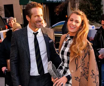 A couple smiles and walks together outdoors in formal attire, with bystanders in the background.