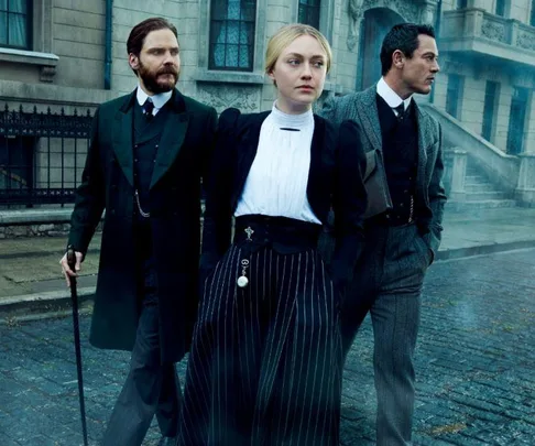 Three characters in period costumes walking on a cobblestone street, likely from "The Alienist" series.