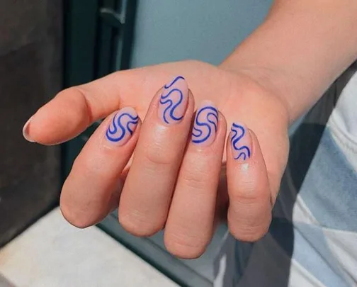 Hand with squiggly blue nail art on short, natural nails.