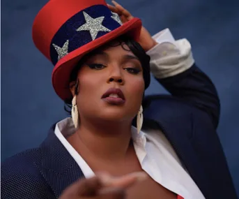 Person wearing a star-patterned red top hat and dark suit posing confidently against a blue background.