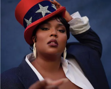 Person wearing a star-patterned red top hat and dark suit posing confidently against a blue background.