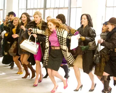 Women rush forward excitedly in a fashion sale frenzy scene, depicting urgency and anticipation.