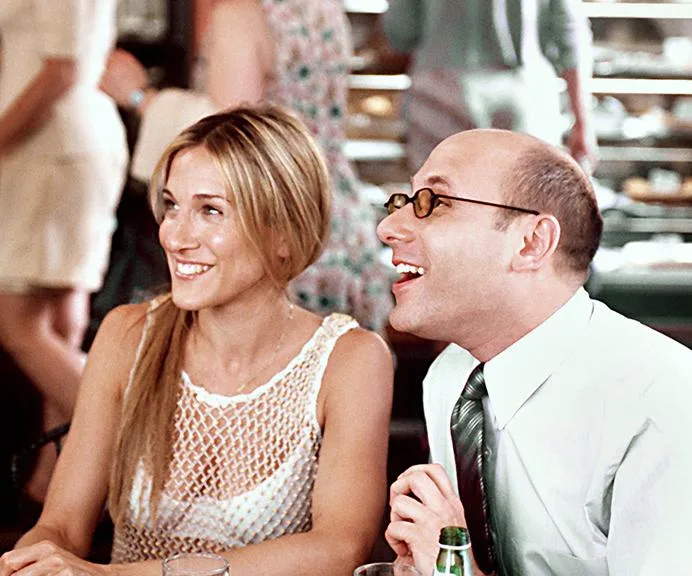 Two people sitting at a cafe table, smiling and chatting, with a background of a bustling restaurant.