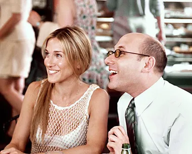 Two people sitting at a cafe table, smiling and chatting, with a background of a bustling restaurant.