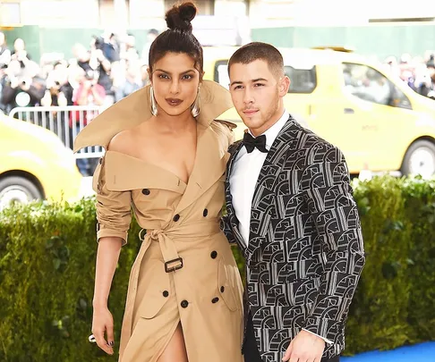 Priyanka Chopra and Nick Jonas pose elegantly in stylish outfits at a public event.