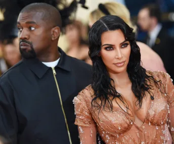 Kim Kardashian and Kanye West at a formal event, Kim in a beaded dress, Kanye in a black jacket.