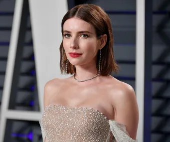 A woman with short hair in a sparkling off-shoulder gown at a formal event.