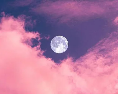 Full moon in a purple sky with pink clouds surrounding it.