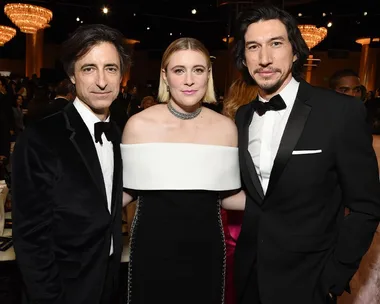 A group of three people dressed formally, two men in suits and a woman in a black and white gown, at an event.