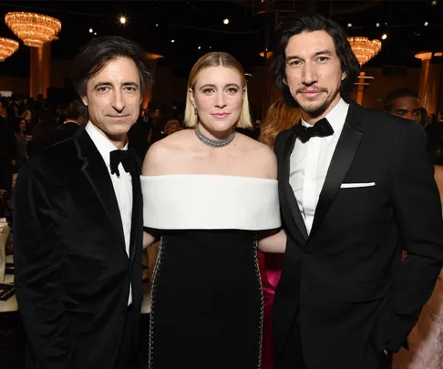 A group of three people dressed formally, two men in suits and a woman in a black and white gown, at an event.