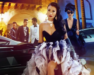 A glamorous group of individuals in formal attire with luxurious cars in the background from "Bling Empire."