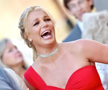 Person in a vibrant red dress laughing at an outdoor event.