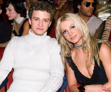 Young couple seated at an event, both smiling at the camera, surrounded by other attendees.