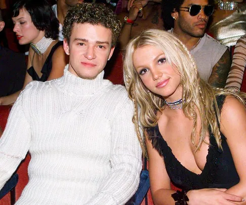 Young couple seated at an event, both smiling at the camera, surrounded by other attendees.