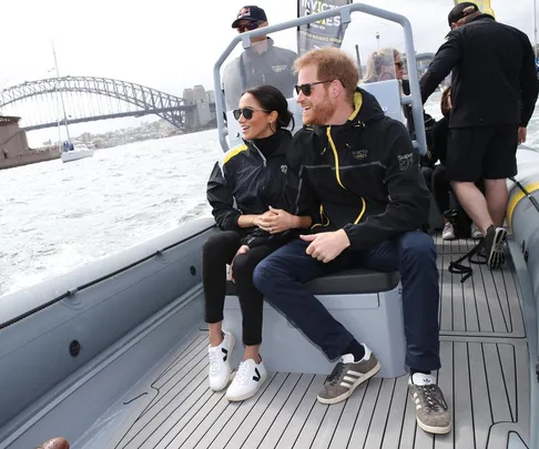 A couple sits on a boat near a bridge, both wearing casual sportswear and sunglasses.