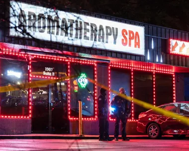 Police officers stand outside Aromatherapy Spa with crime scene tape visible at night.