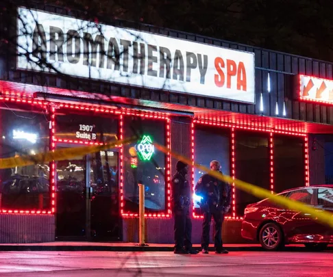 Police officers stand outside Aromatherapy Spa with crime scene tape visible at night.