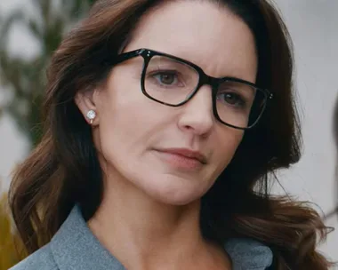 A woman with dark hair and glasses looks thoughtful, possibly a scene from "Deadly Illusions."