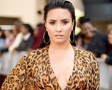 Woman in a leopard print top with hoop earrings, gazing directly at the camera.