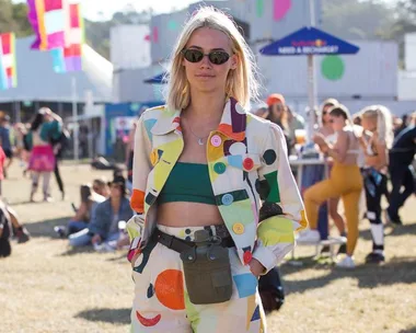 Festival-goer in colorful outfit with sunglasses at Splendour in the Grass 2021, outdoors with people and tents in background.