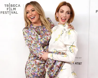 Two people in floral outfits posing and smiling at the Tribeca Film Festival event backdrop.