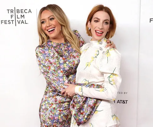 Two people in floral outfits posing and smiling at the Tribeca Film Festival event backdrop.