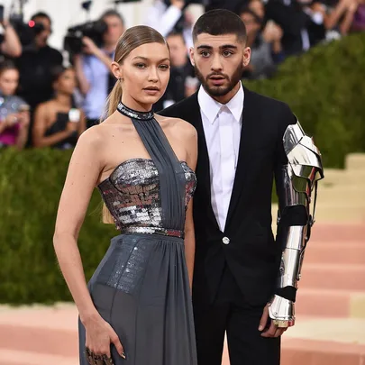 Gigi Hadid at the Met Gala with a male companion wearing a metallic arm piece, posing for cameras.