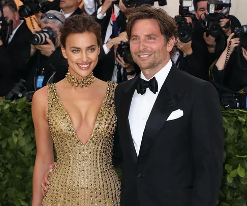 A couple poses together at a formal event, with photographers capturing the moment in the background.