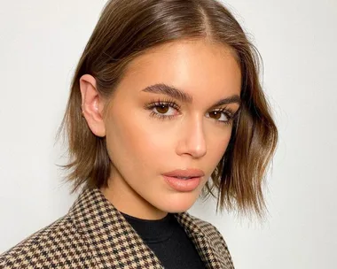 Person with bob haircut and natural makeup, wearing a checkered blazer, looking at the camera.