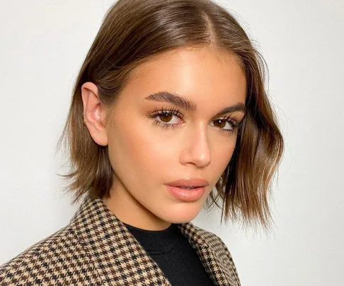 Person with bob haircut and natural makeup, wearing a checkered blazer, looking at the camera.