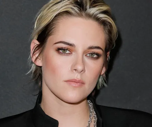 Kristen Stewart poses with short blond hair and a black outfit at an event.