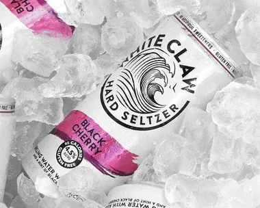 White Claw Black Cherry hard seltzer can on ice, displaying wave logo and calorie info.