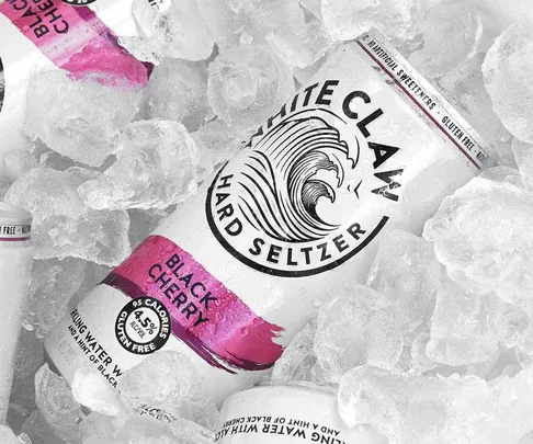 White Claw Black Cherry hard seltzer can on ice, displaying wave logo and calorie info.