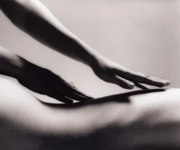 Hands providing a soothing massage on a person's back, in a calming grayscale image.