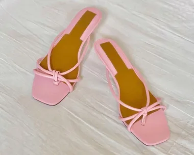 Pink square-toe sandals with thin straps on a white surface.