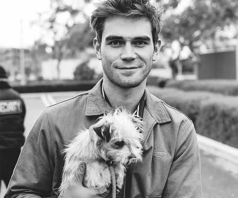 Black and white photo of KJ Apa holding a small dog