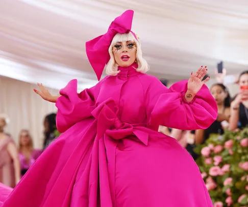 A person in an extravagant, bright pink gown with dramatic bow and headdress at the Met Gala 2021.