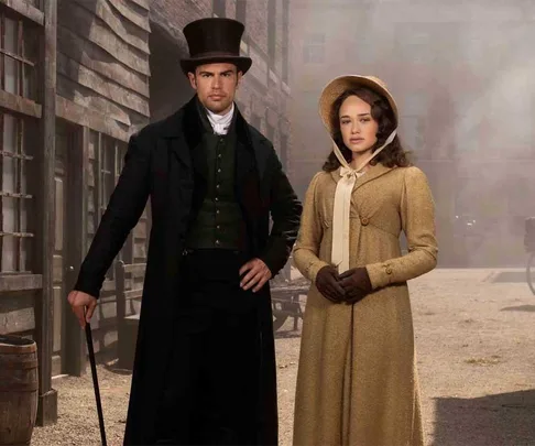 A man and a woman in period costumes stand in a dusty street setting from "Sanditon" Season 2.