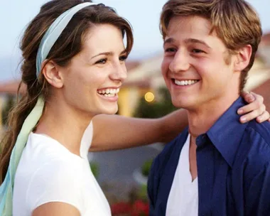 Two characters from "The O.C." smiling and embracing, featuring Ryan and Marissa in a sunny outdoor setting.