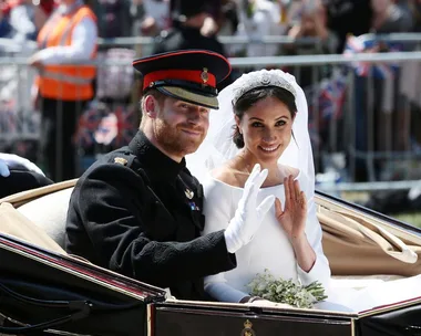 Prince Harry and Meghan Markle wave from a horse-drawn carriage during their wedding procession.