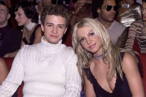 Young couple seated closely at an event, smiling at the camera.