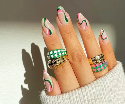 Checkerboard rings on fingers with colorful wavy nail art, featuring green, pink, and gold patterns.