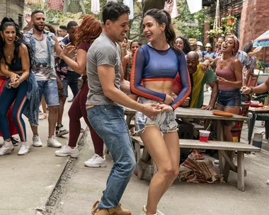 People dancing joyfully at a daytime outdoor gathering in a vibrant neighborhood scene.