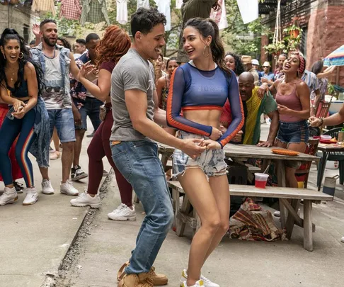 People dancing joyfully at a daytime outdoor gathering in a vibrant neighborhood scene.