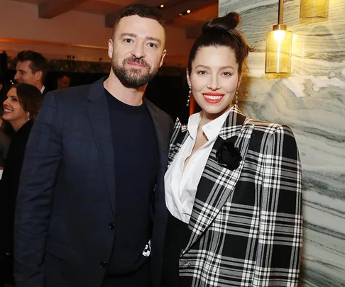 "Justin Timberlake and Jessica Biel smiling at an event, with elegant attire and soft lighting."