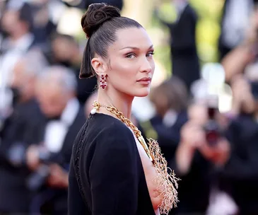 Bella Hadid in a unique Schiaparelli necklace dress at Cannes 2021, looking over her shoulder.