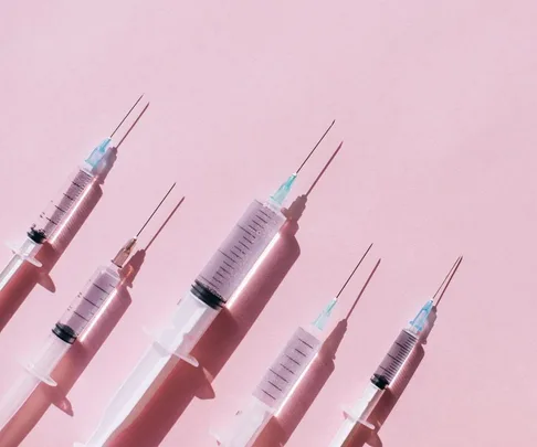 Syringes aligned on a pink background, illustrating preparation for Botox treatment.