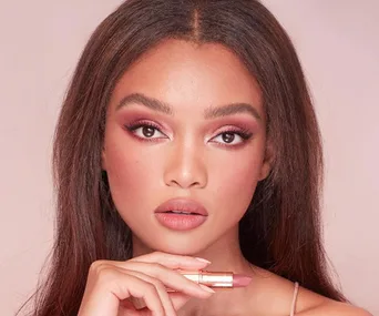 A model showcasing Charlotte Tilbury Pillow Talk lipstick with neutral pink makeup look.