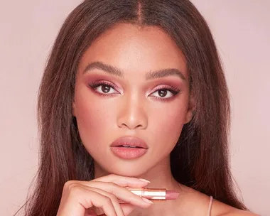 A model showcasing Charlotte Tilbury Pillow Talk lipstick with neutral pink makeup look.